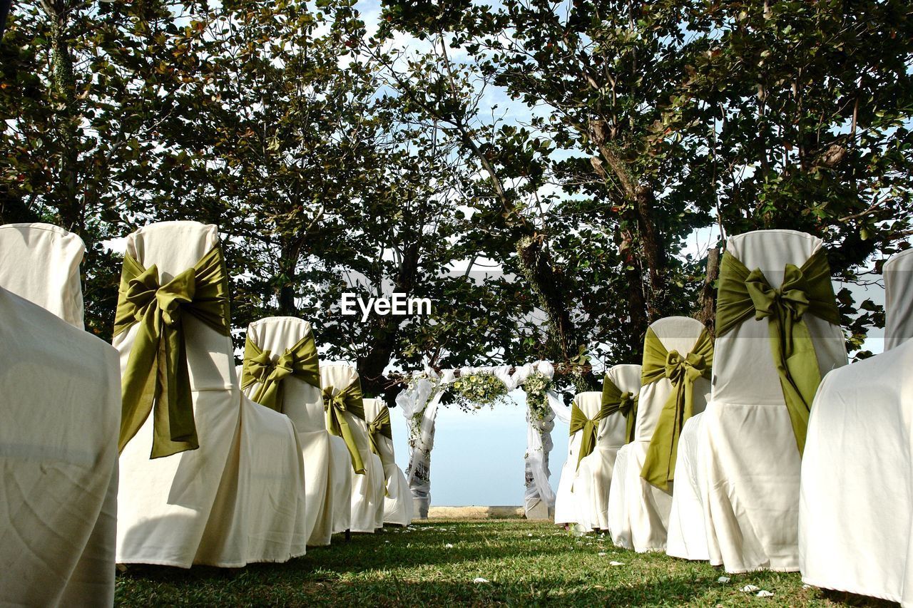 Chair covered with fabrics arranged on field against trees