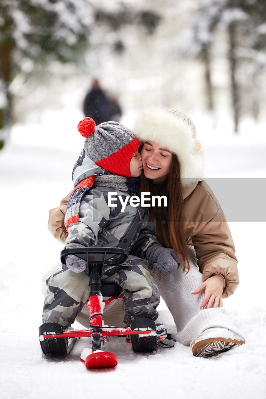 Son embracing with mother on snow covered land