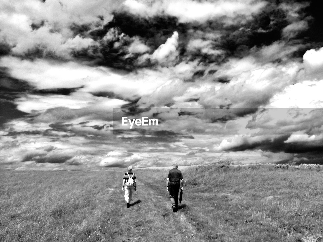 PEOPLE WALKING ON FIELD AGAINST SKY