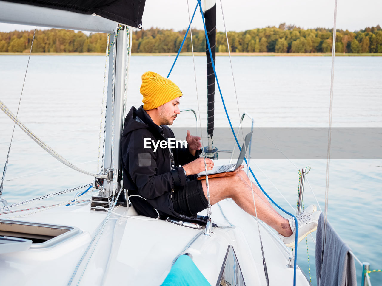 Person working with laptop on a sailing yacht during sailing by lake, remote work concept person