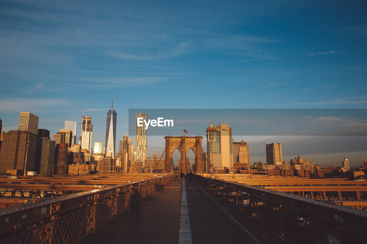 Brooklyn bridge in city against blue sky