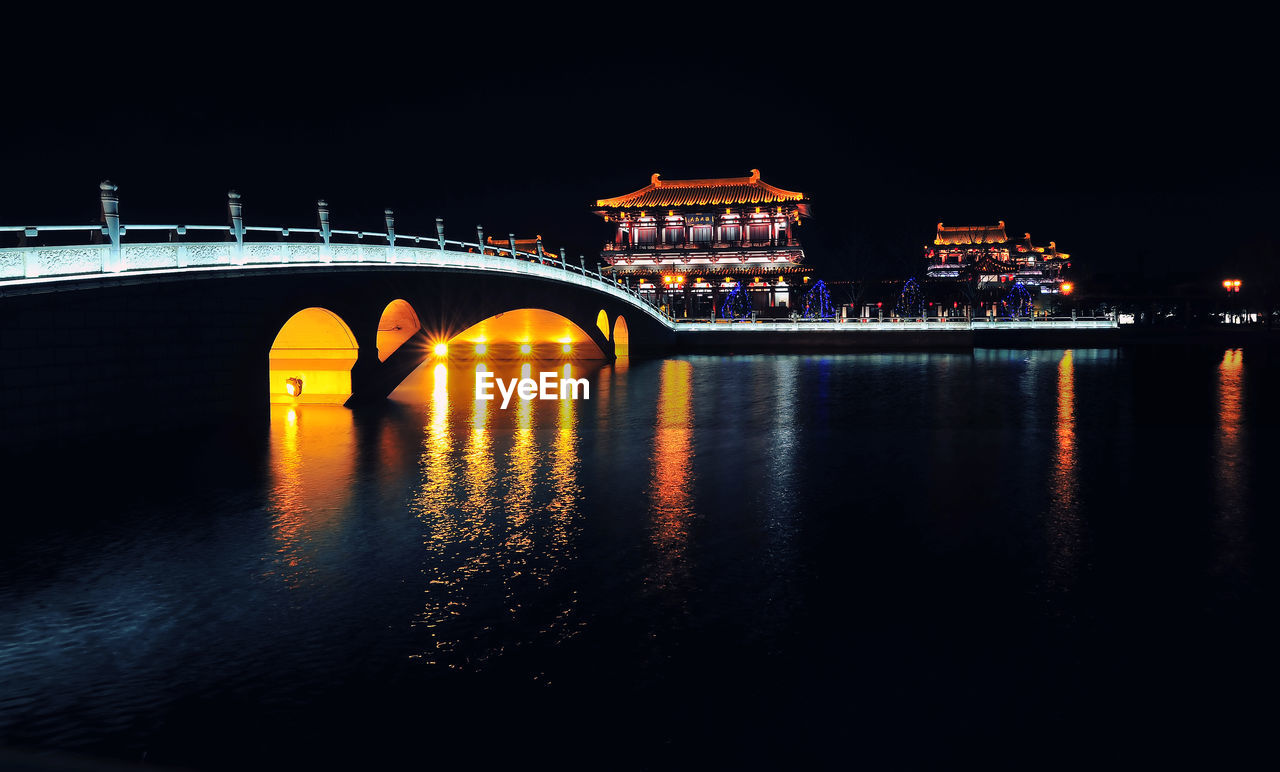 Illuminated bridge over river at night