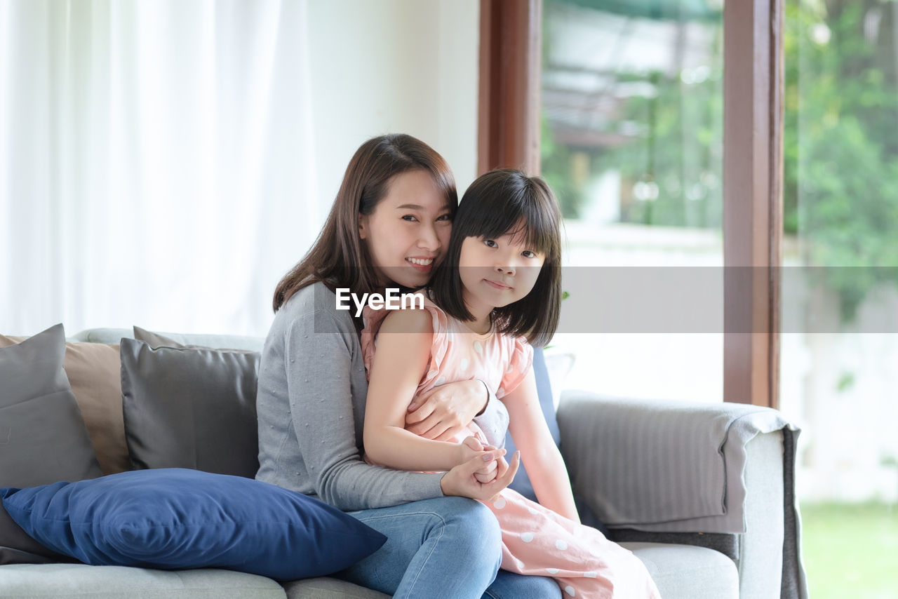 Asian mother feel hapiness during hug her cute daughter with love and care at home