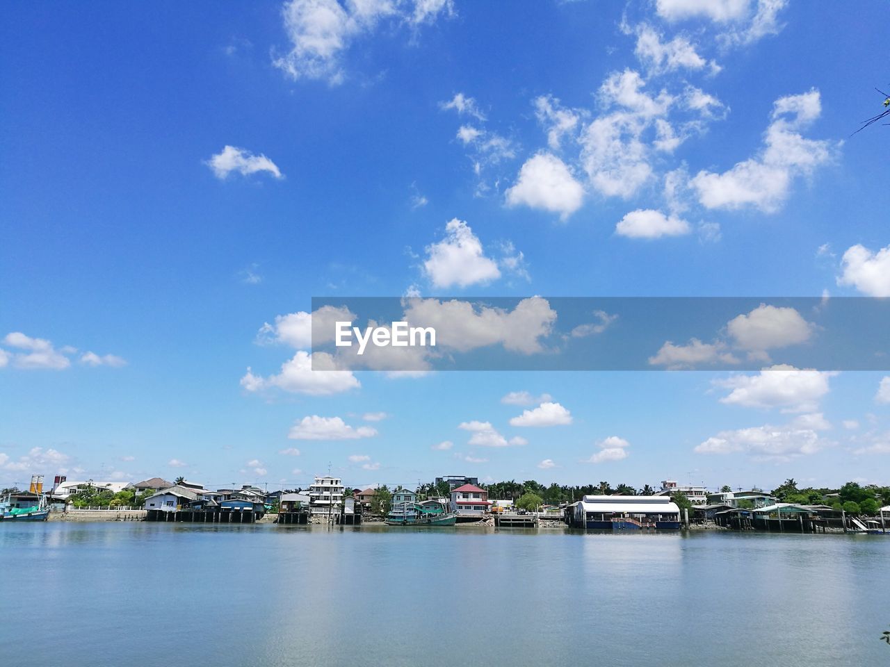 Lake by houses against blue sky