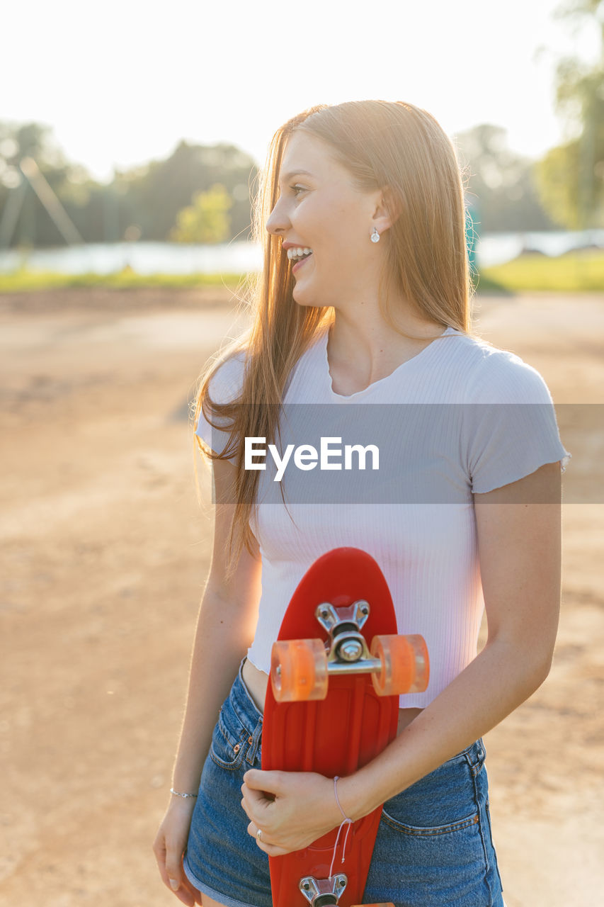 Portrait of a happy teenage girl holding a skateboard