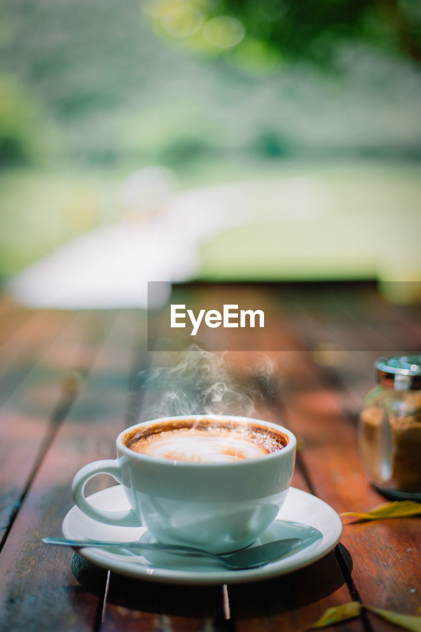 COFFEE CUP ON TABLE AGAINST CAFE