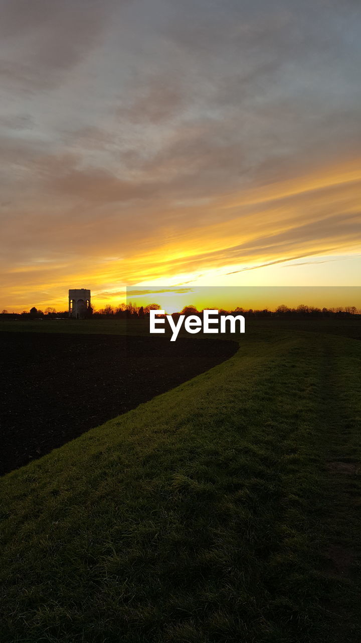 SCENIC VIEW OF SILHOUETTE FIELD AGAINST SKY AT SUNSET