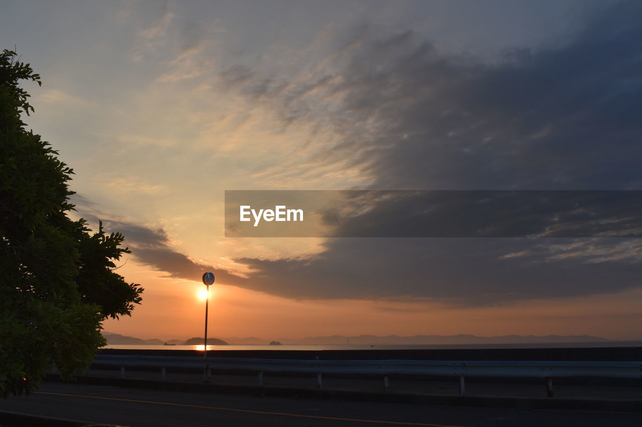 SILHOUETTE TREES BY SEA AGAINST ORANGE SKY