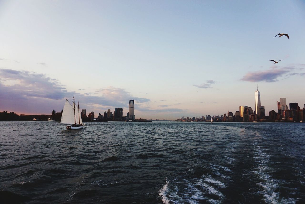 Boat sailing in sea with city in background