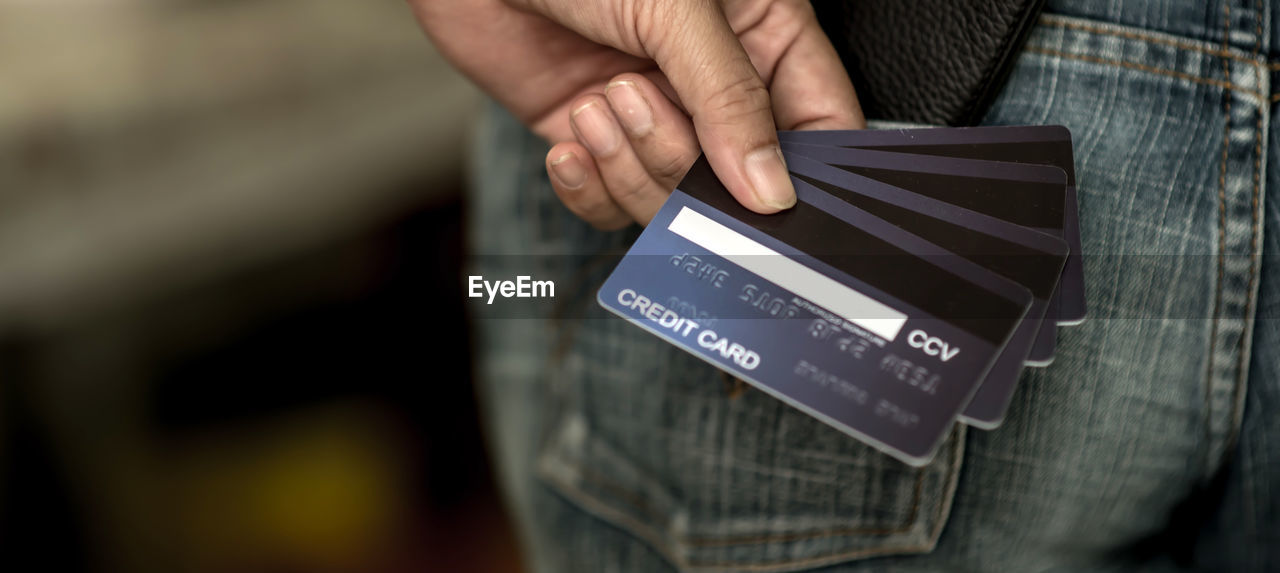 Credit cards in many back pocket of jeans in hand