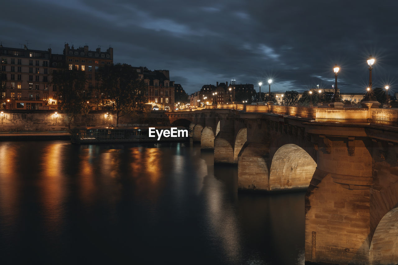 Illuminated bridge over river against sky at night