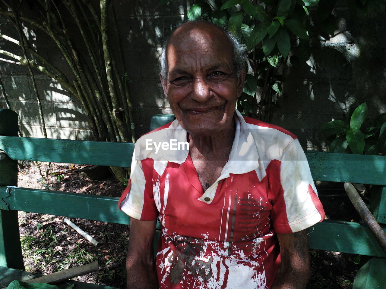 Portrait of smiling senior man sitting on bench at park