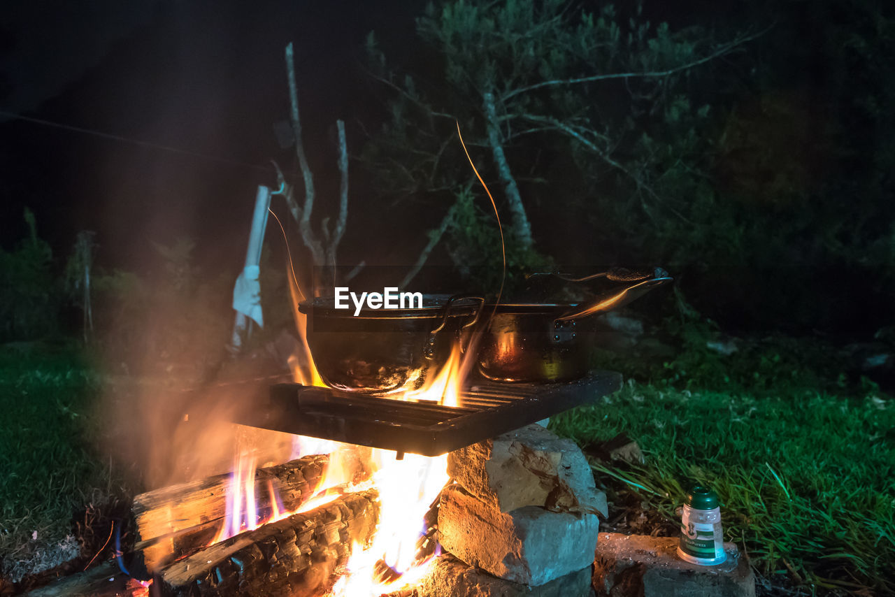 Outdoor cooking in pot over bonfire at night