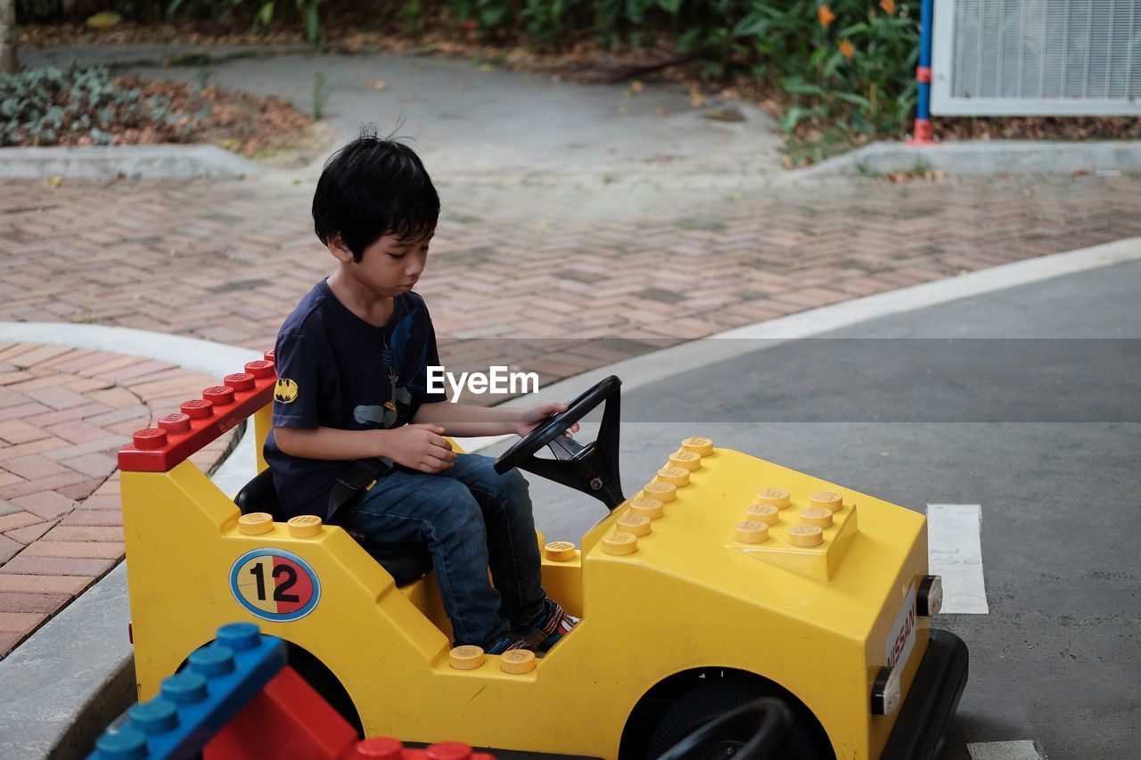 REAR VIEW OF BOY LOOKING AT TOY CAR