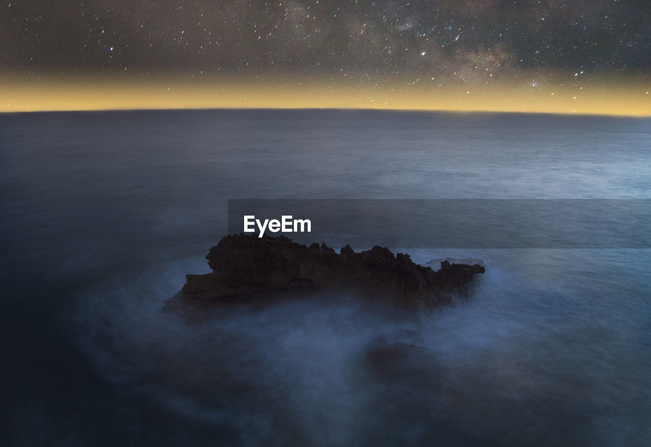 ROCKS IN SEA AGAINST SKY AT NIGHT