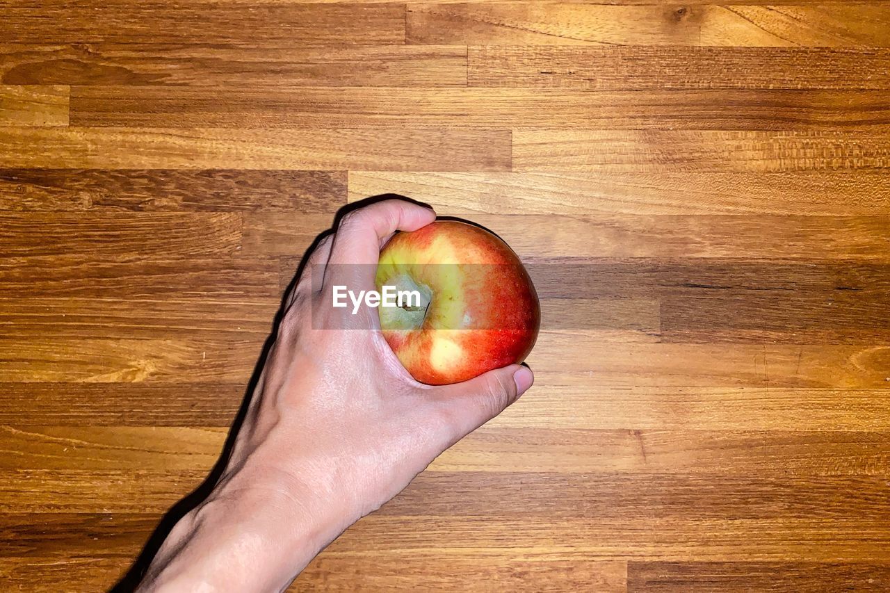 HIGH ANGLE VIEW OF HAND HOLDING APPLE