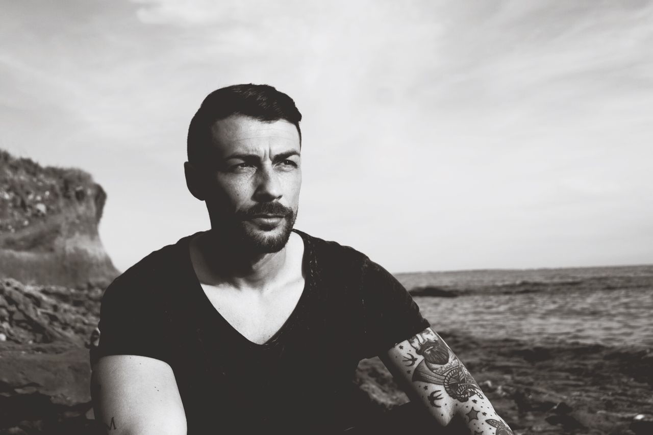 Man sitting on rock against sea at beach