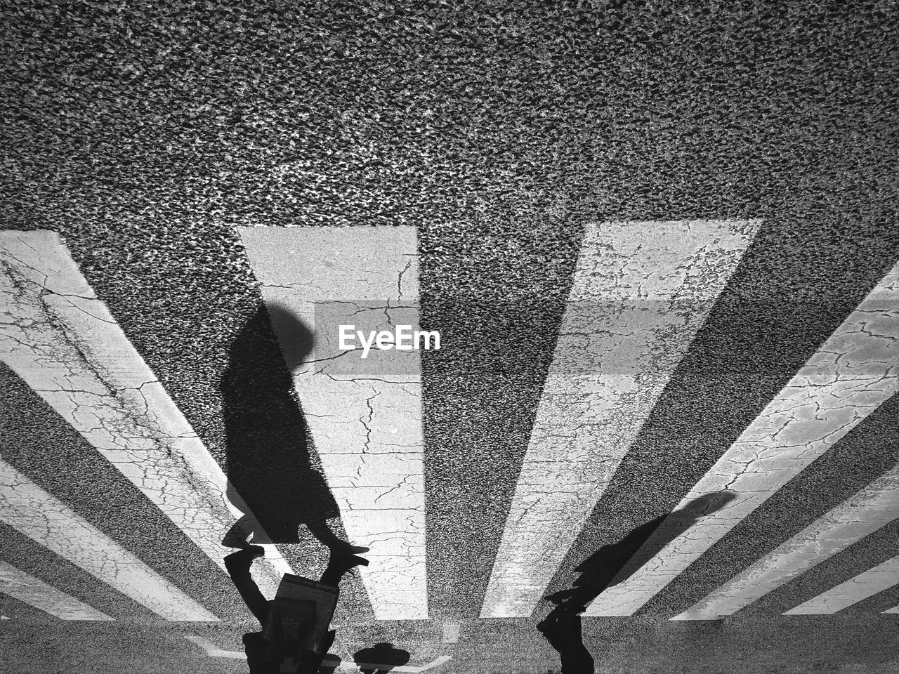 Upside down view of people walking on zebra crossing