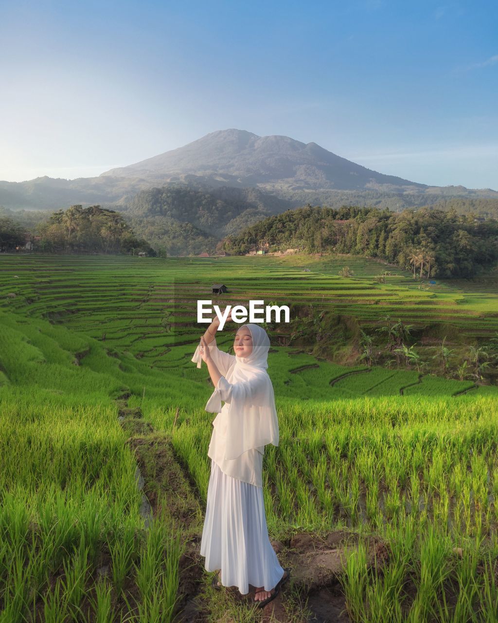 Woman standing on field by mountain against sky