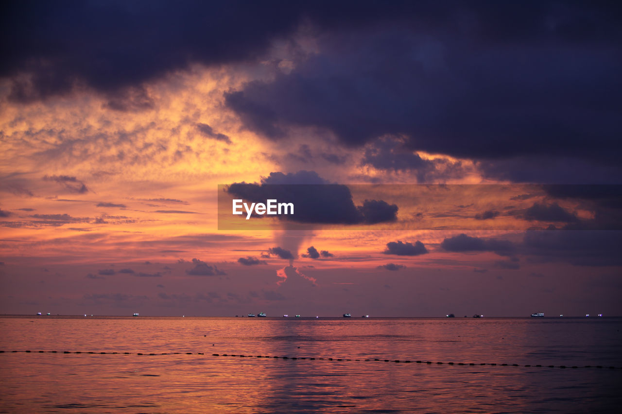 Scenic view of sea against cloudy sky during sunset