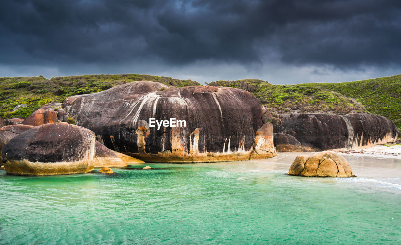 Rocks in sea against cloudy sky