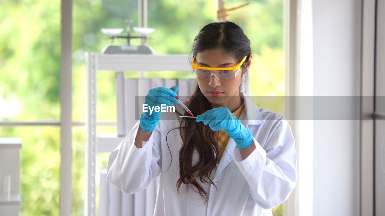 Woman examining chemical while standing in laboratory