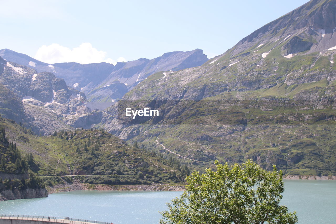 SCENIC VIEW OF MOUNTAINS BY LAKE AGAINST SKY