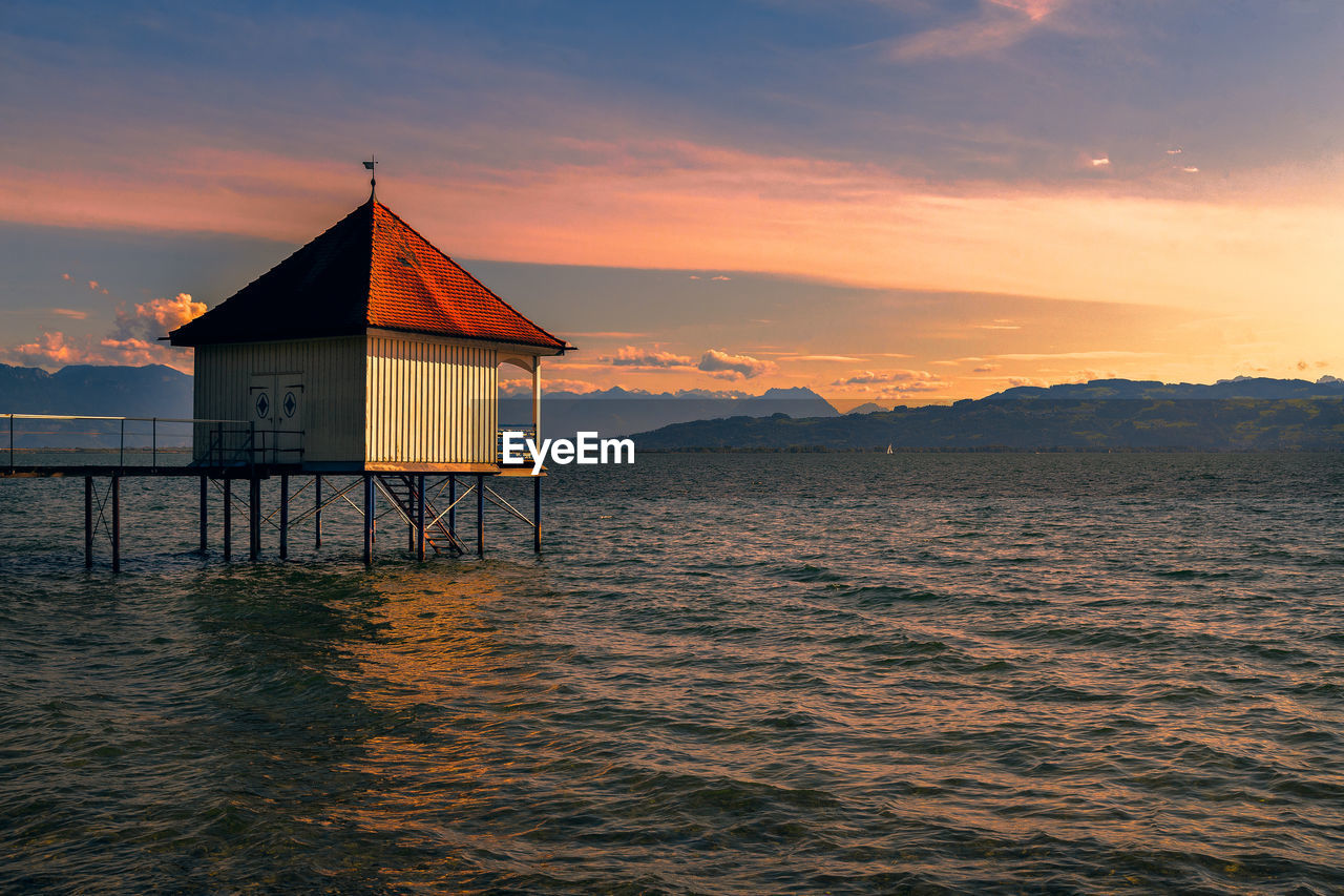 BUILT STRUCTURE ON SEA AGAINST SKY DURING SUNSET