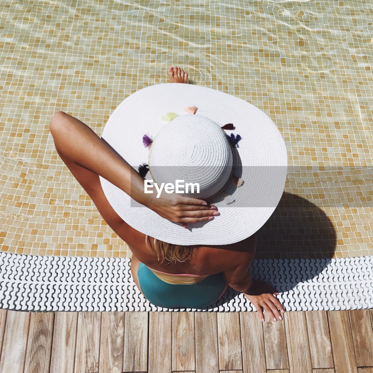 High angle view of woman with hat sitting at poolside