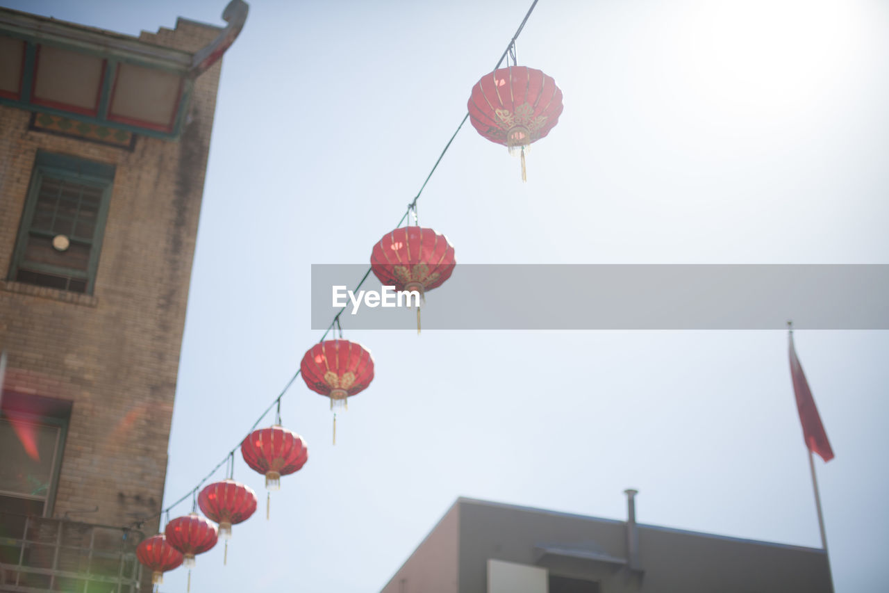 Low angle view of chinese lanterns hanging against clear sky on sunny day