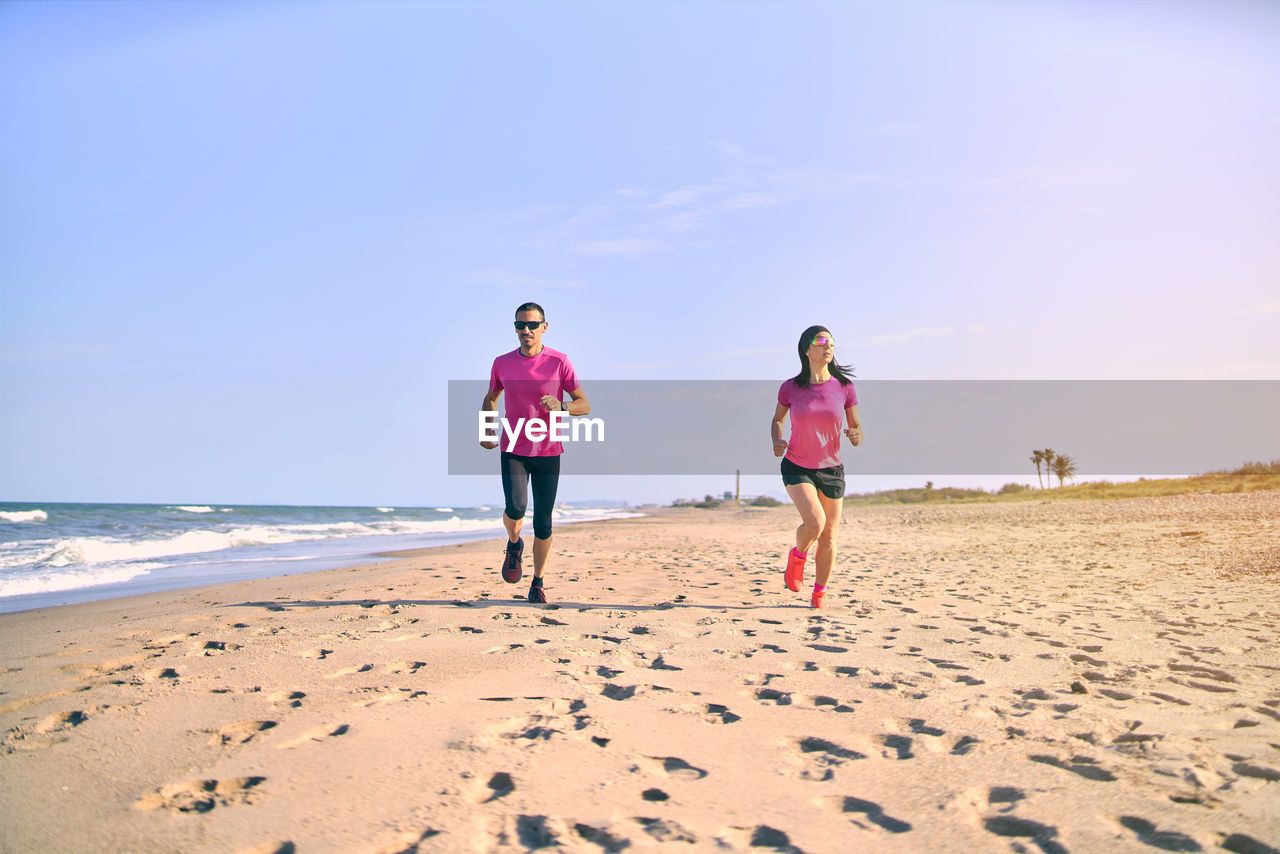 Rear view of women on beach against sky