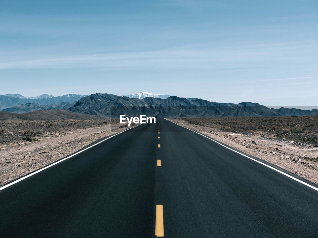 Empty road by mountains against sky