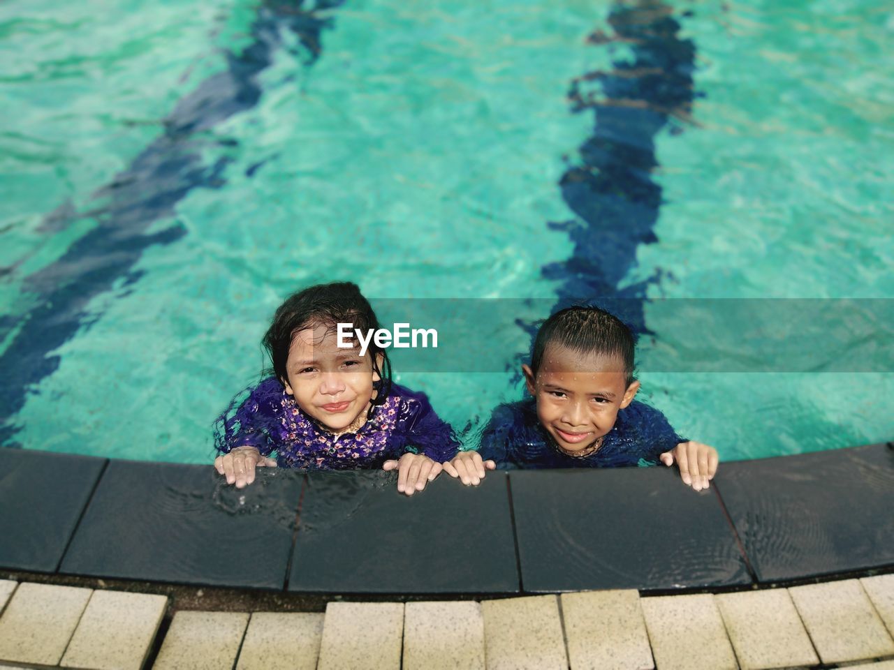 High angle portrait of siblings swimming in pool