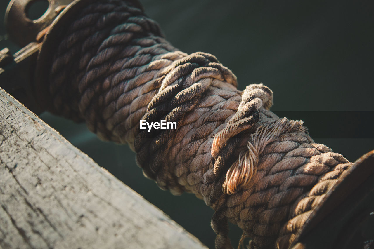 Close-up of rope rolled up on pulley at lake