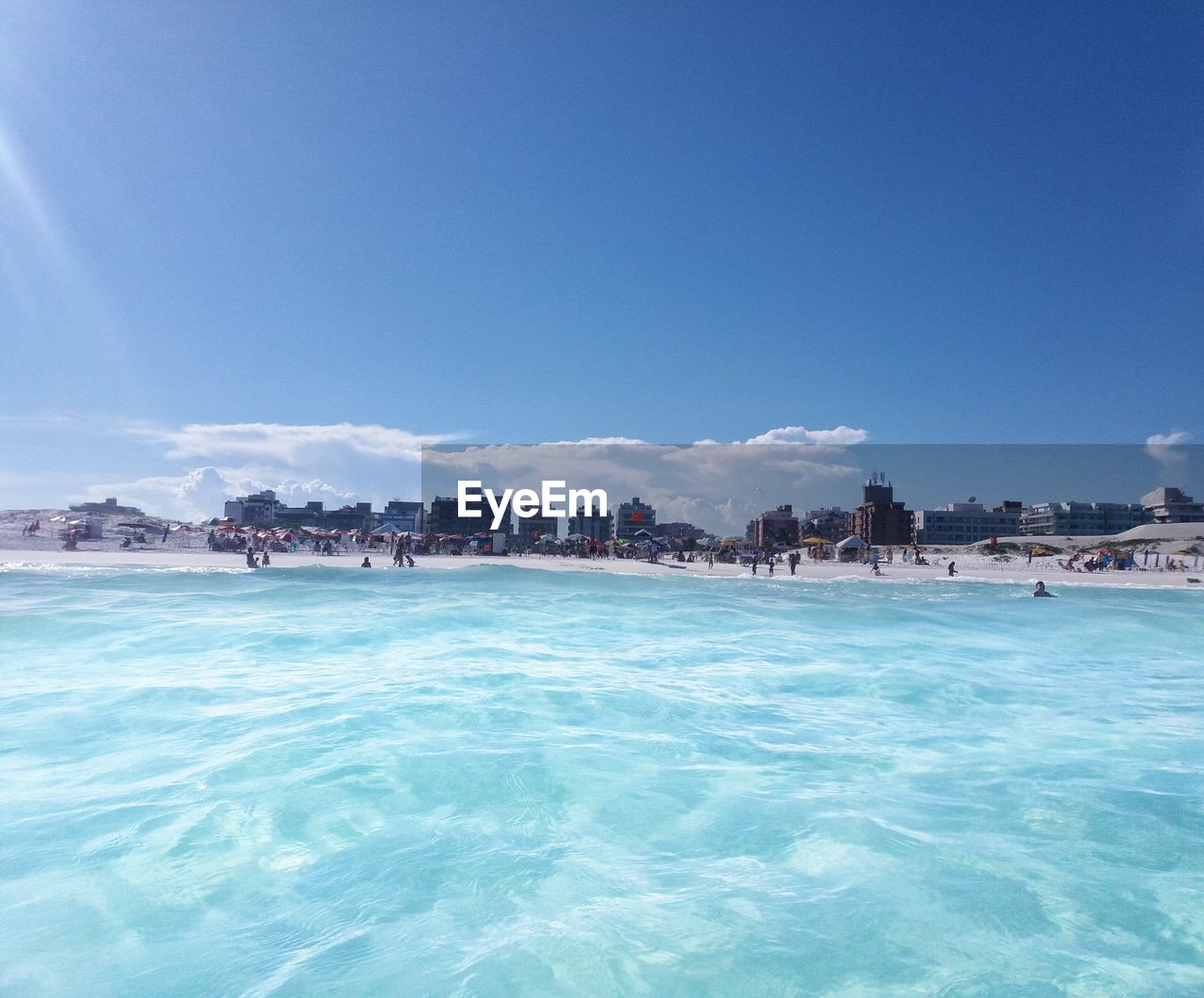 Scenic view of beach against blue sky on sunny day