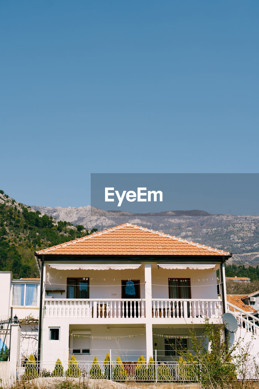 HOUSE BY BUILDING AGAINST CLEAR SKY