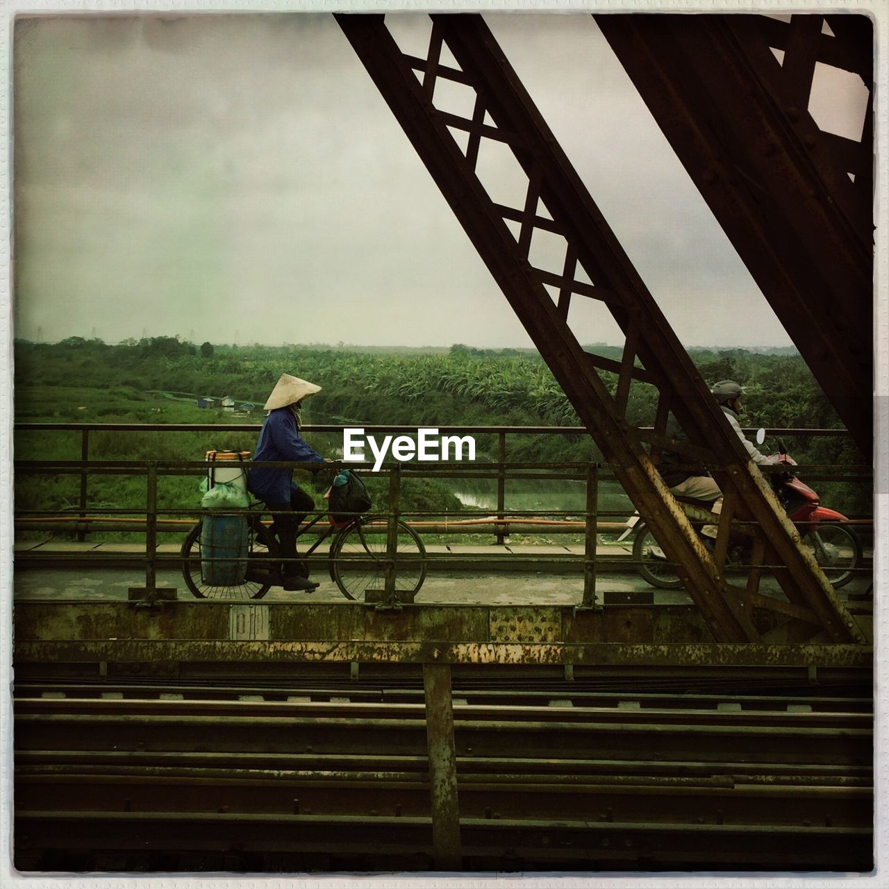 Side view of person riding bicycle on bridge