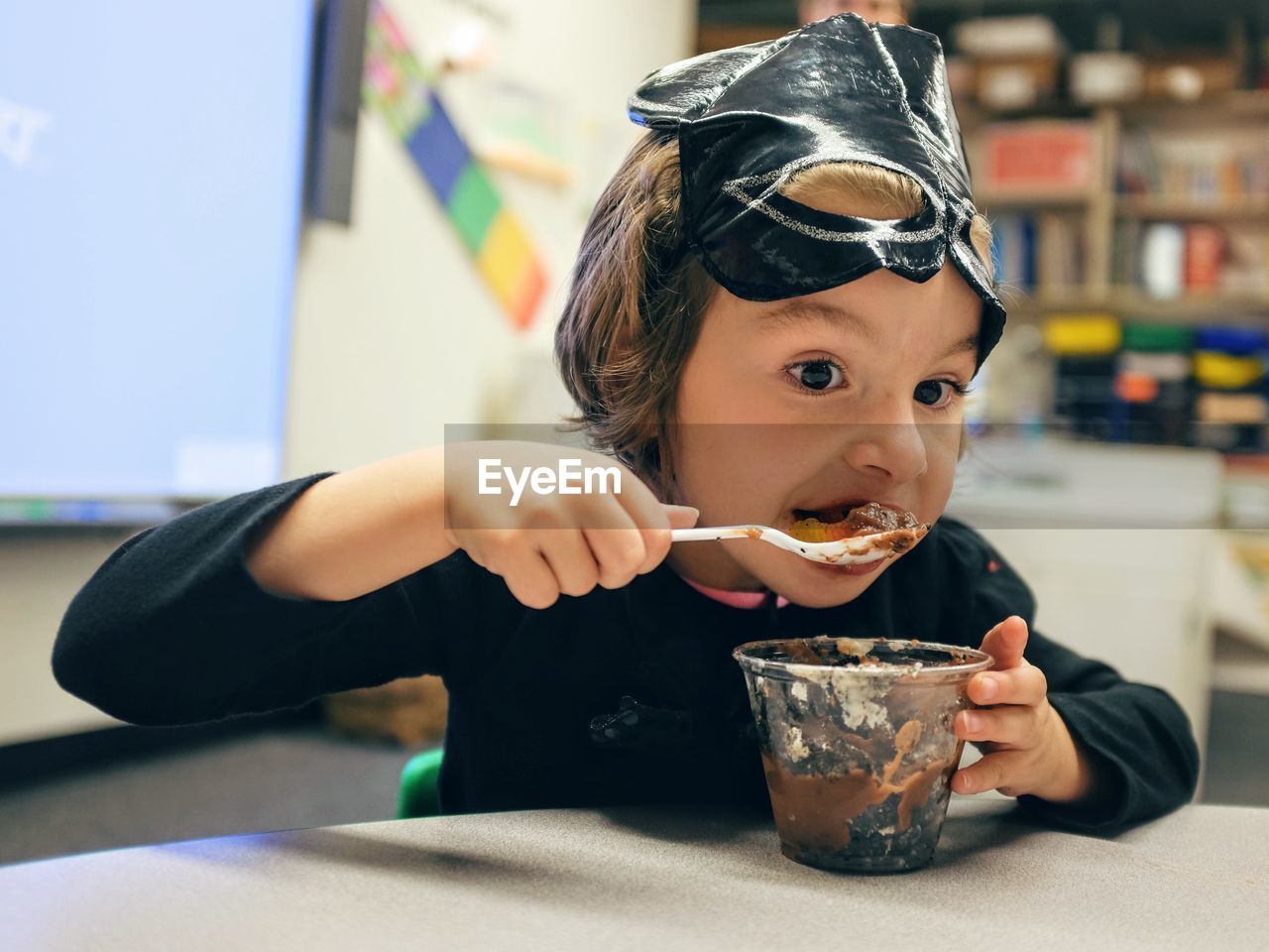 Portrait of girl eating ice cream by table