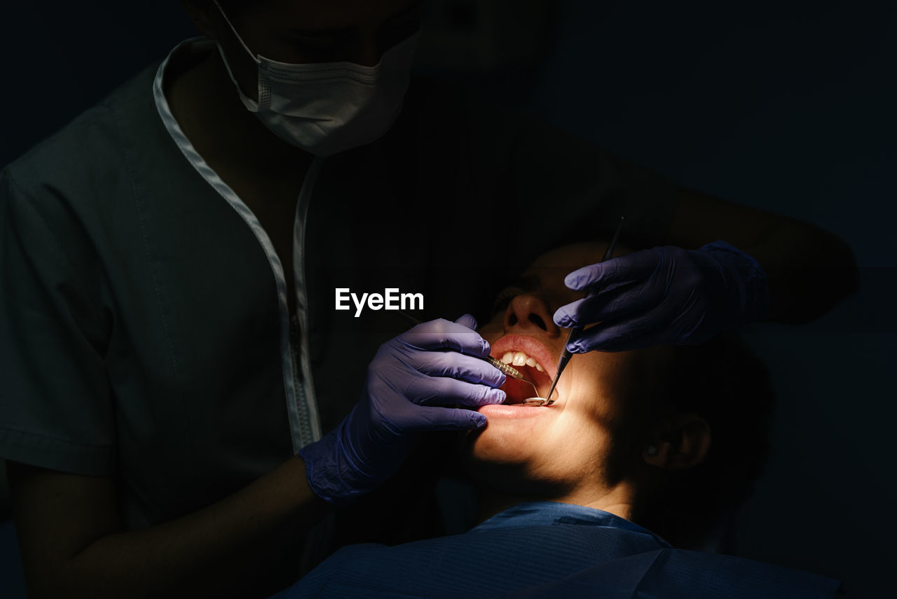 Close-up of dentist examining woman in clinic