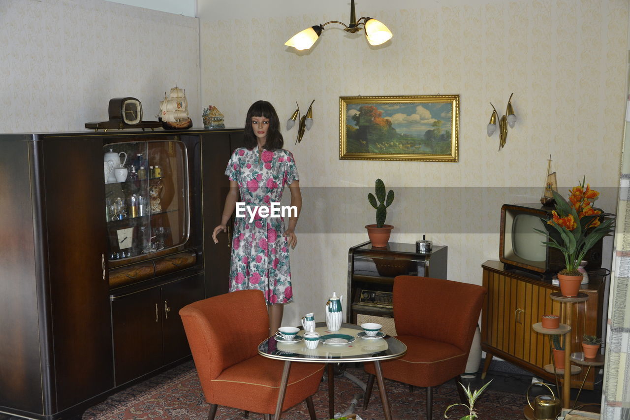 WOMAN STANDING ON TABLE WITH CHAIRS AT HOME