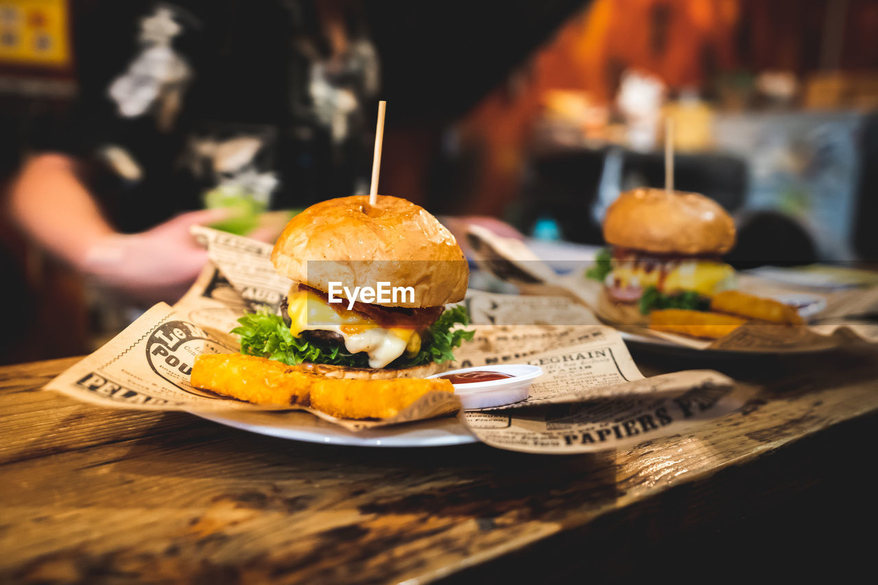 CLOSE-UP OF HAND HOLDING FOOD IN RESTAURANT