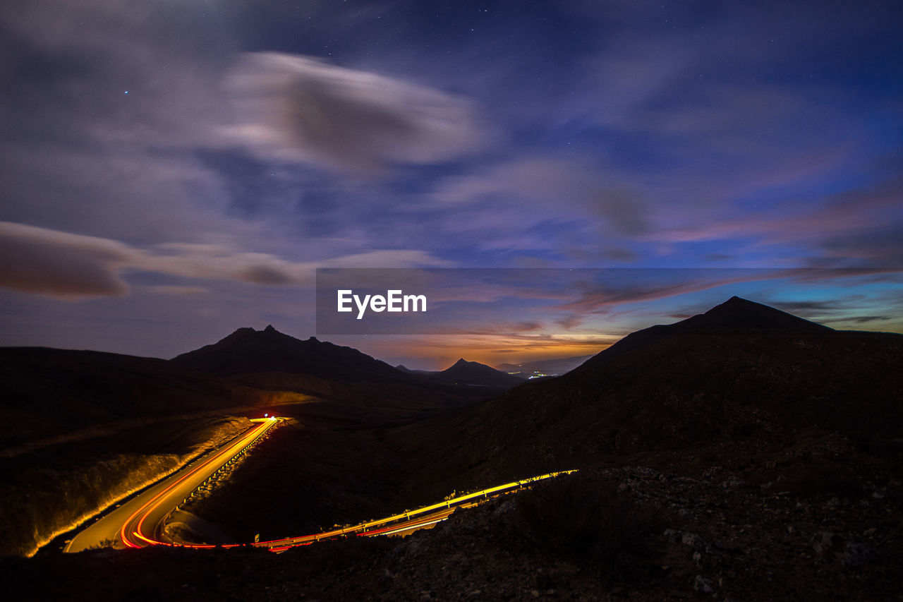 Aerial view of illuminated mountains against sky at sunset