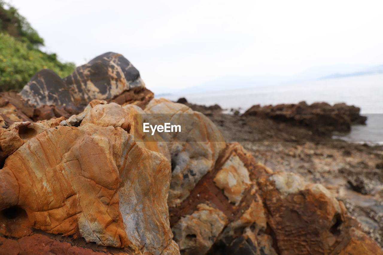 Close-up of rock formation on beach against sky