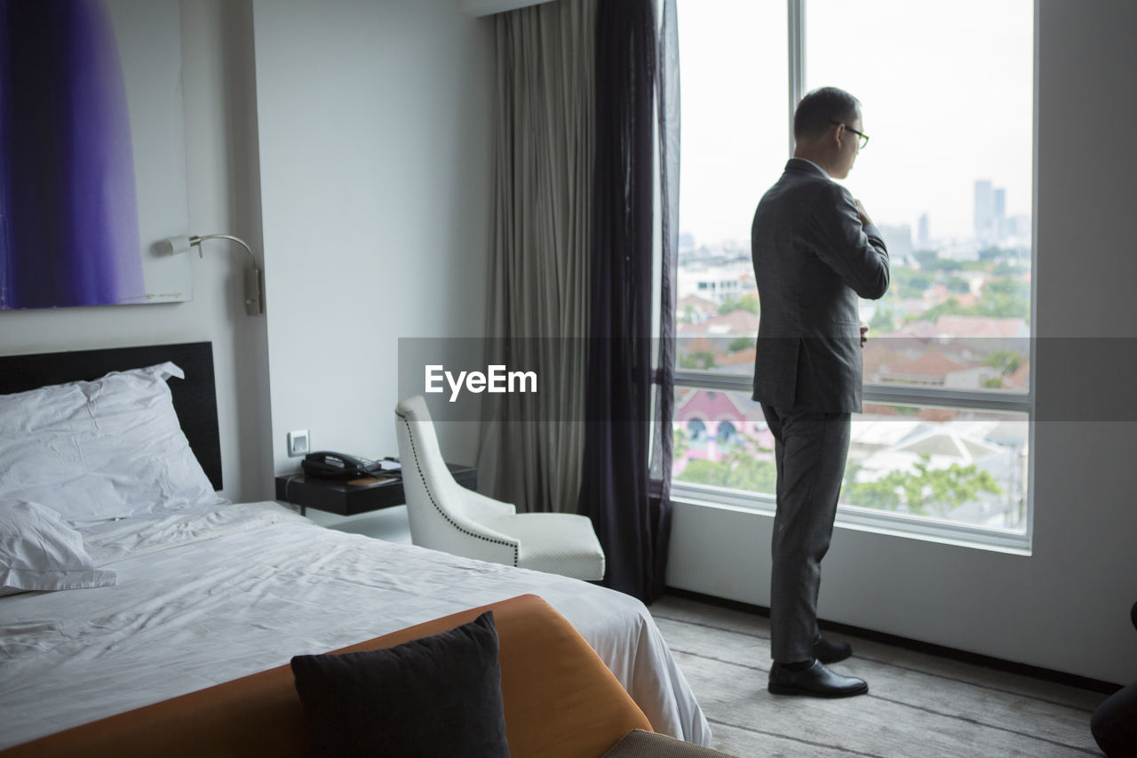 Rear view of businessman standing by window at home