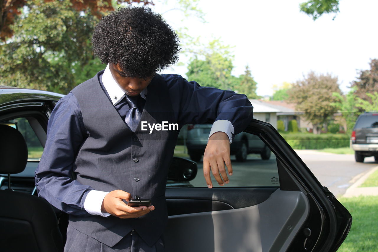 REAR VIEW OF MAN STANDING BY CAR