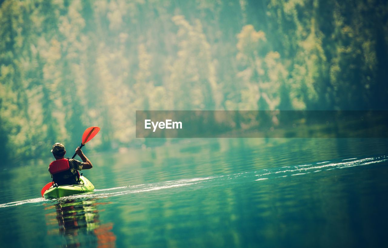 Rear view of man kayaking on lake