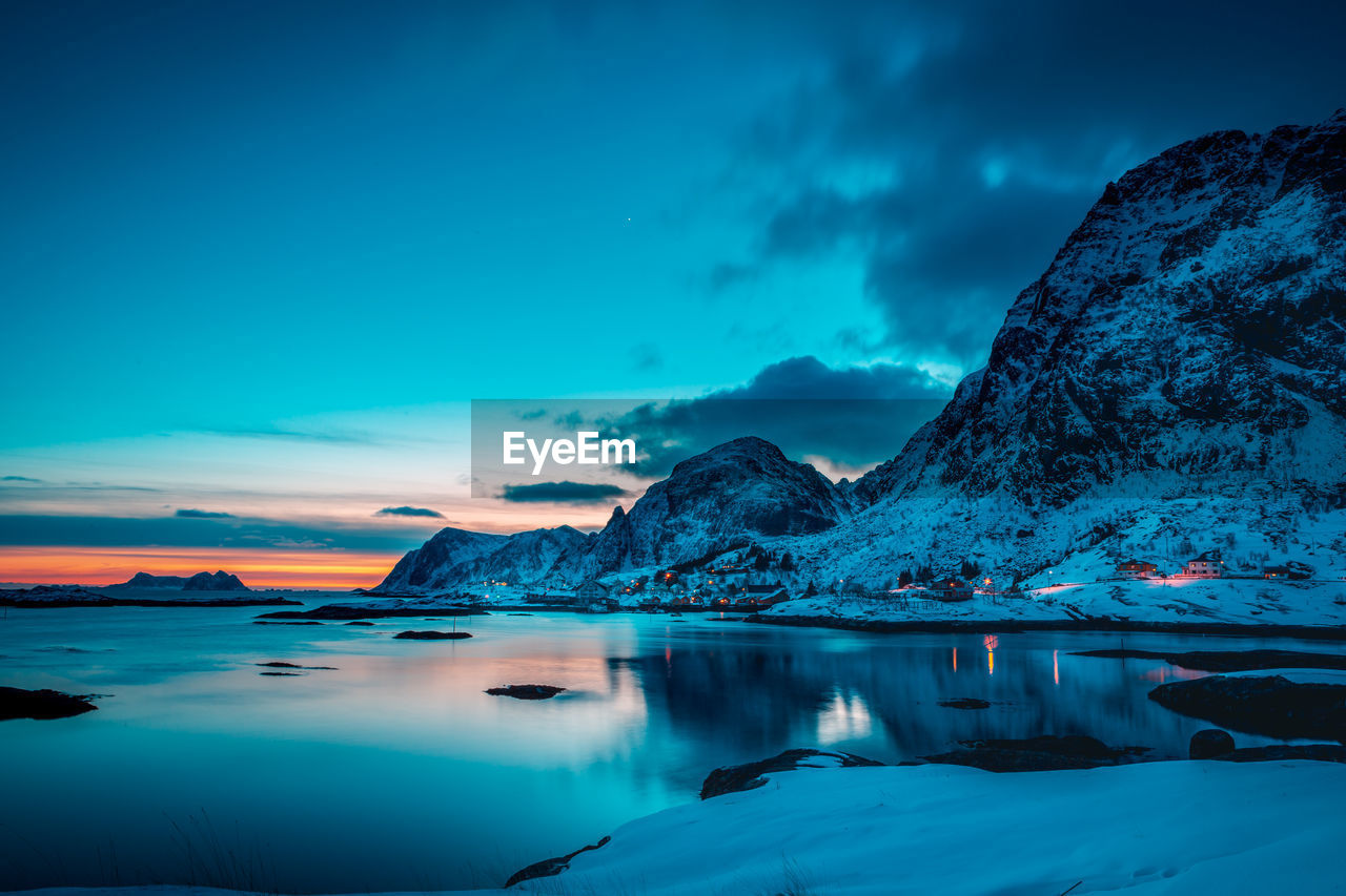 Scenic view of lake and snowcapped mountains against sky during sunset