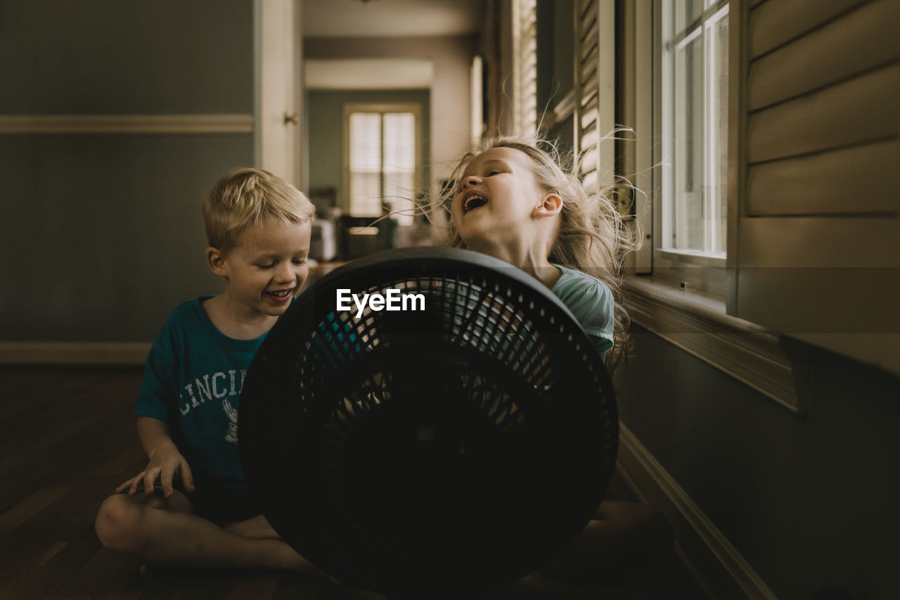 Children sitting in front of fan