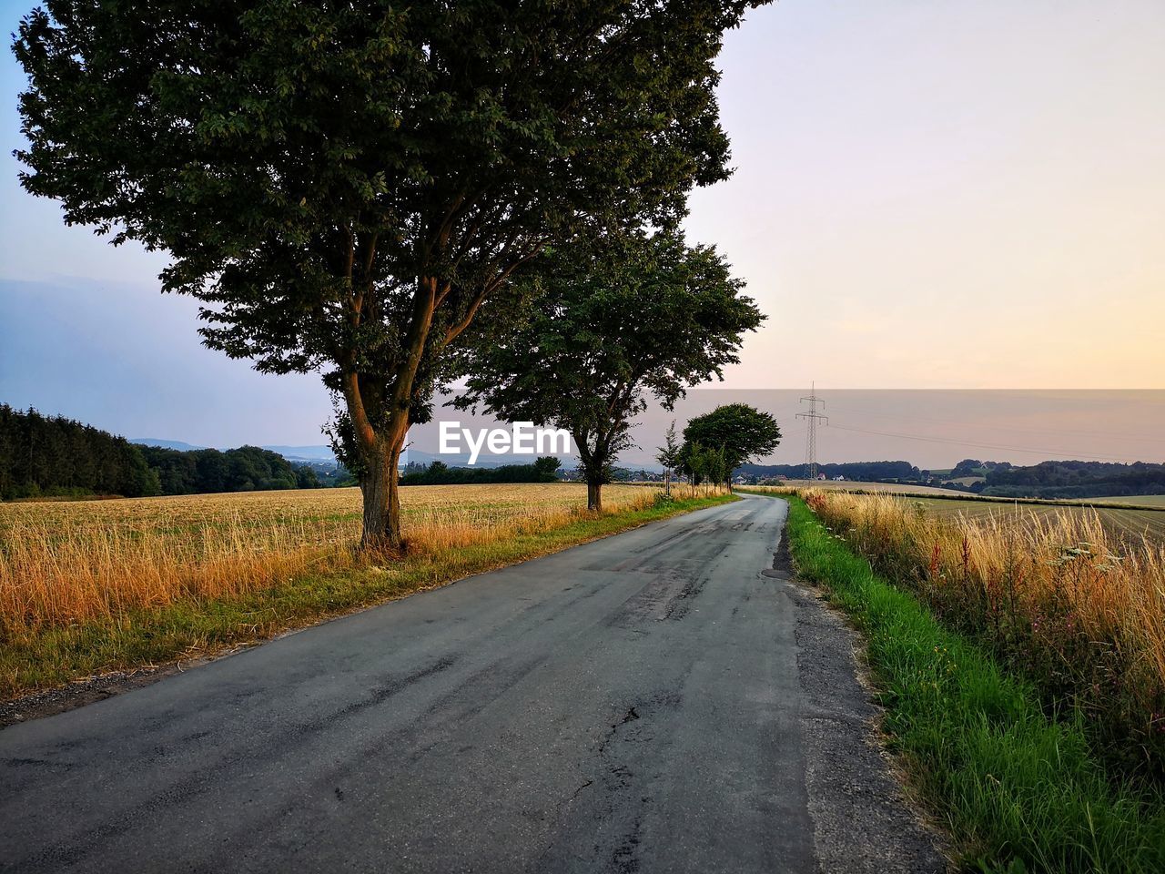 ROAD AMIDST FIELD AGAINST SKY DURING SUNSET