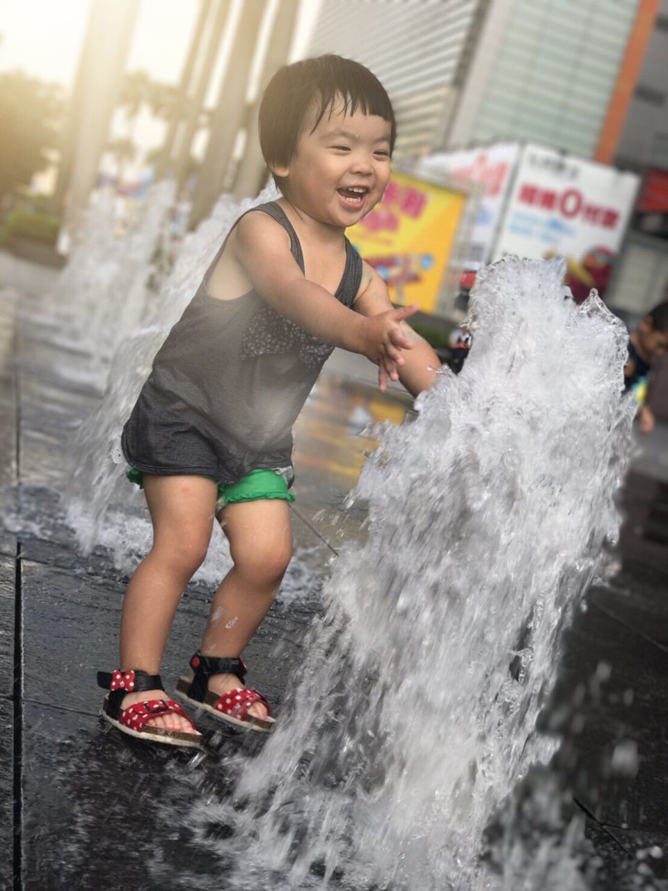 HAPPY BOY PLAYING IN WATER AT PARK